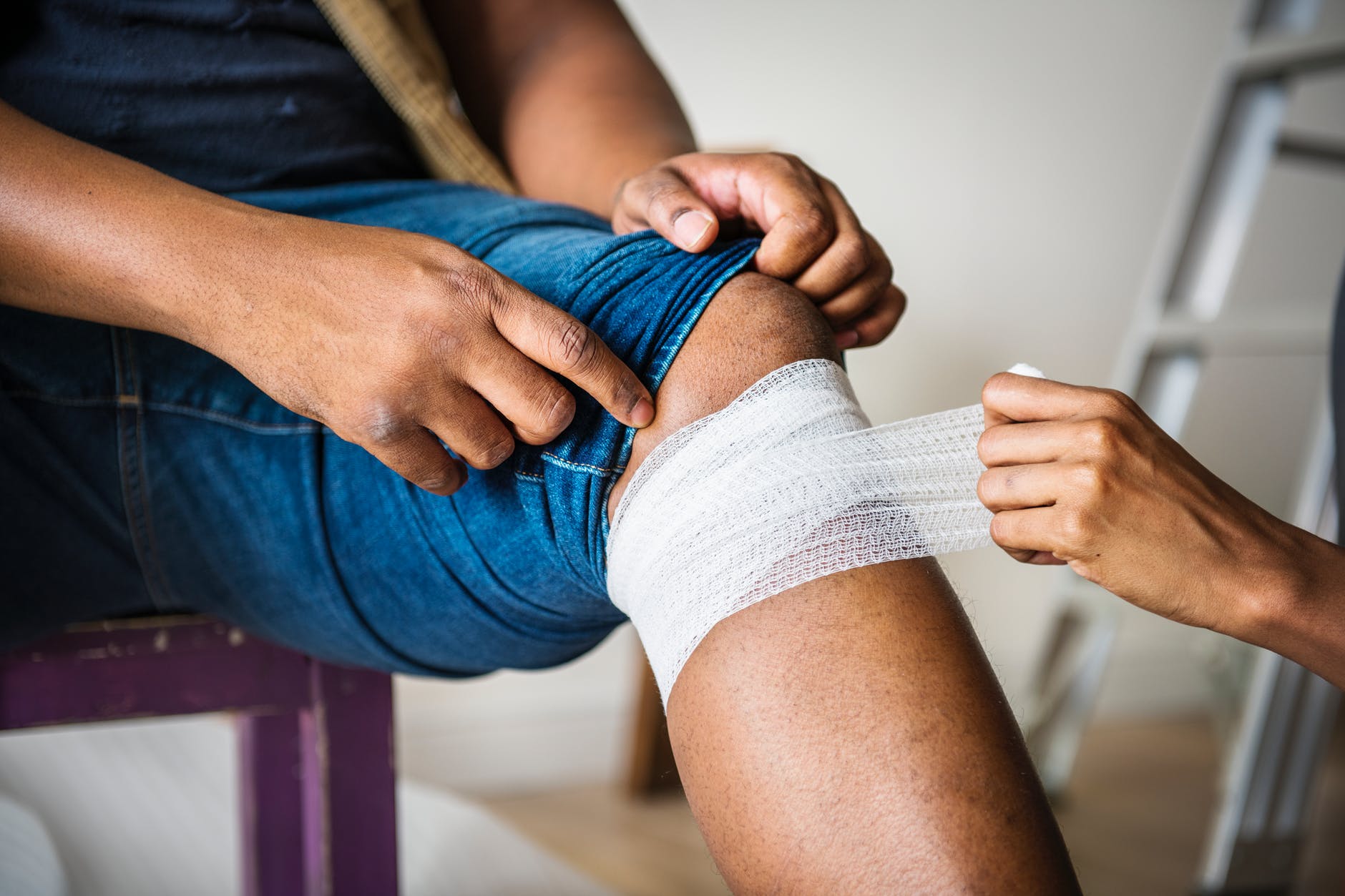 person putting bandages on another person s knee